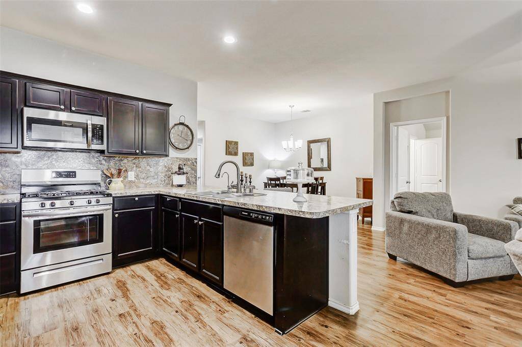 A stainless steel dishwasher makes post-meal cleanup quick and effortless. A smartly placed counter overhang discreetly houses your trash can, keeping the space clean and clutter-free.