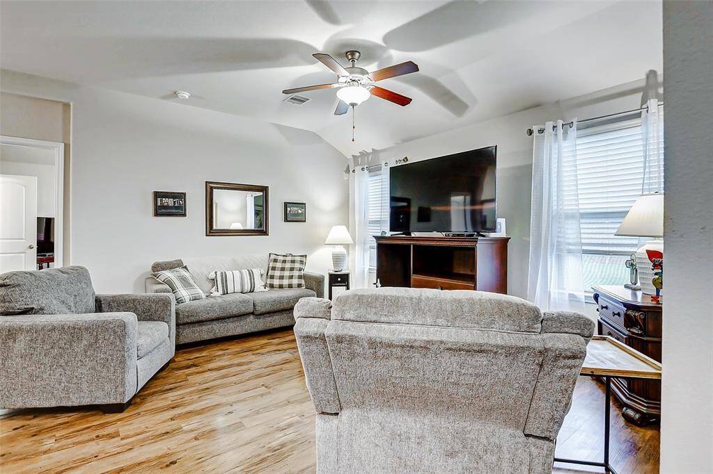 A high ceiling with a ceiling fan provides year-round comfort, while the gleaming vinyl plank flooring adds warmth and durability.