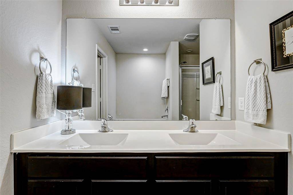 The ensuite bathroom is thoughtfully designed to combine comfort, functionality, and style. It features dual sinks set in a spacious vanity, providing ample room for morning routines or shared use.