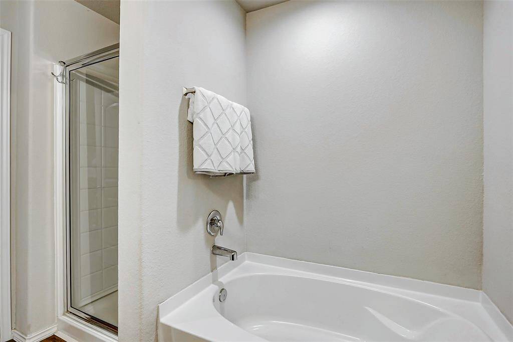 A large garden tub invites you to unwind in a soothing soak, while the separate glass-enclosed shower offers a quick and refreshing alternative.