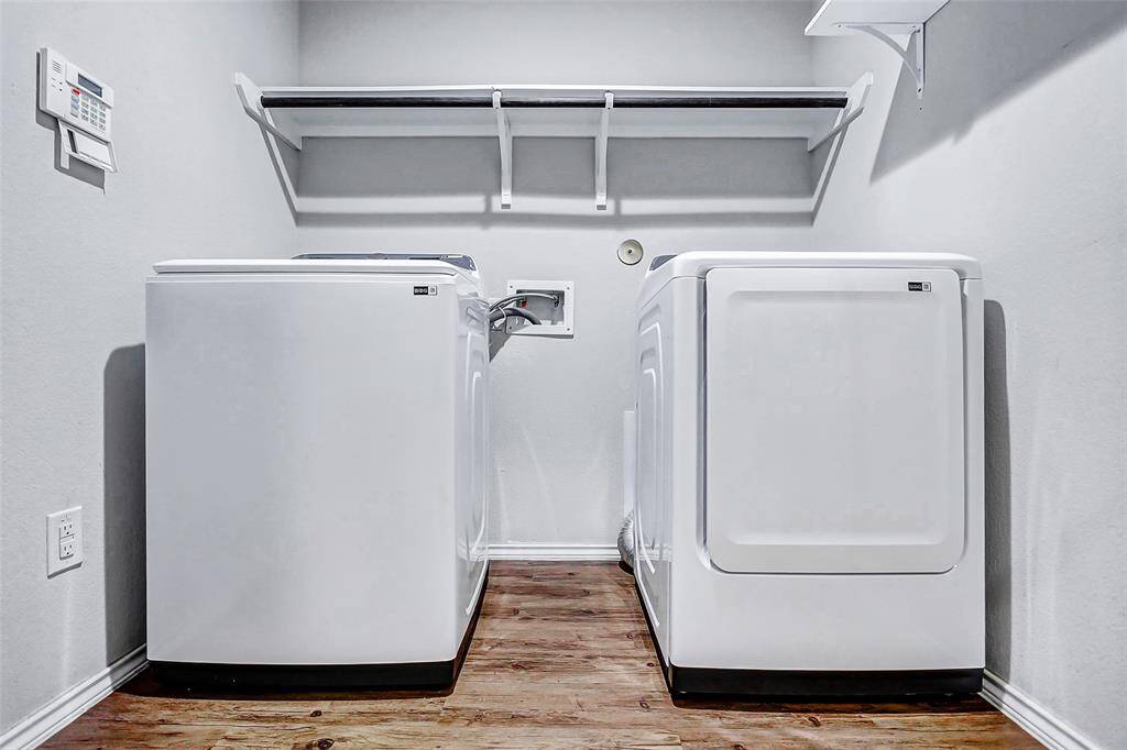 The laundry room offers ample space to accommodate a full-size washer and dryer, along with overhead shelving and a convenient hanging rod—perfect for storing supplies and streamlining daily laundry tasks.