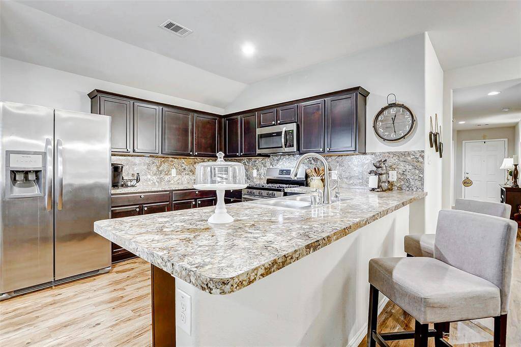 An oversized breakfast bar extends from the kitchen, offering additional seating and serving as the perfect spot for casual dining, morning coffee, or conversations with guests while you cook.