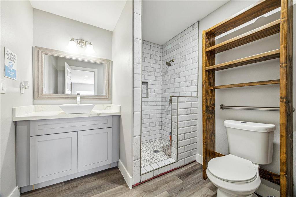 Bright primary bath featuring a shower, toilet with wall shelves and elegant sconces.