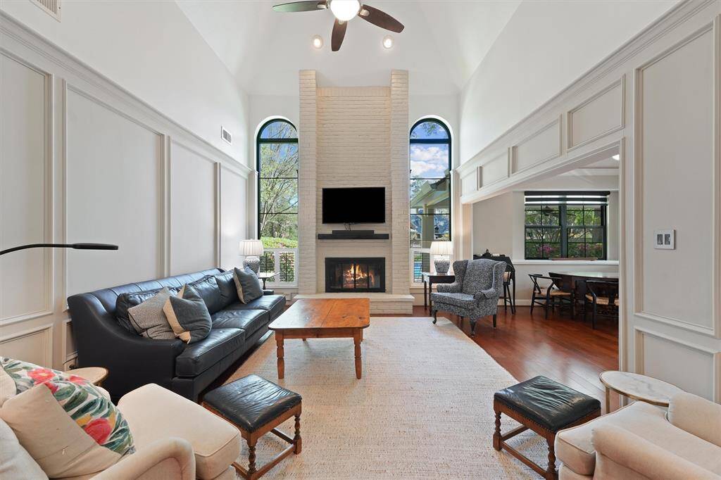 Living room with high ceilings, views of the backyard and a cozy fireplace.