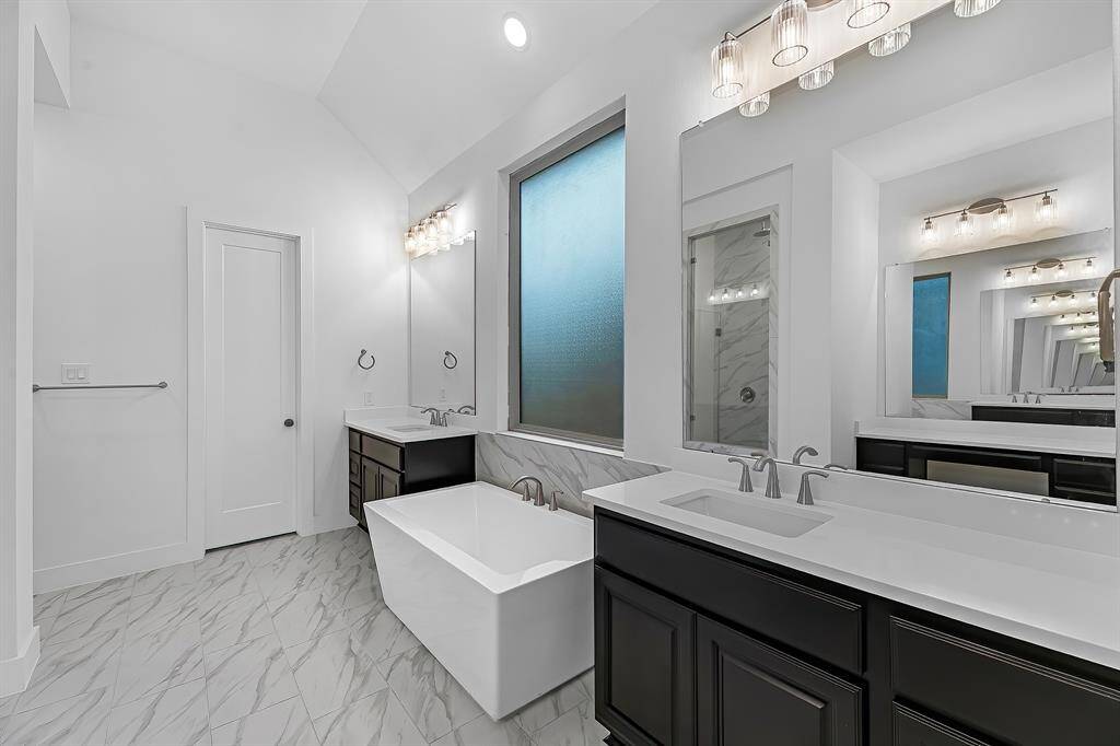 Stunning primary bathroom with double sinks and standing designer soaking tub.