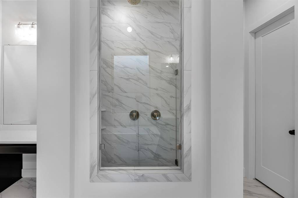The primary shower has floor to ceiling tile and rain shower head.