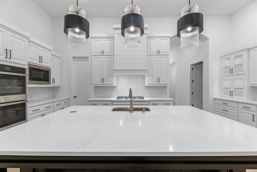 Designer lighting, cabinet hardware, and stainless appliances in the kitchen.