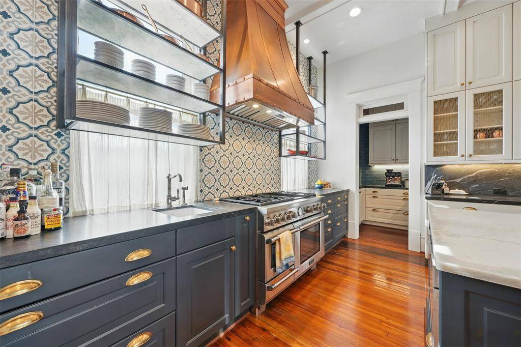 Every inch of the kitchen has been carefully curated. Floor-to-ceiling cabinetry, exquisite tilework, and open shelving preserve the flow of natural light from original windows. A chef’s prep sink sits conveniently next to the range—designed for both form and function.