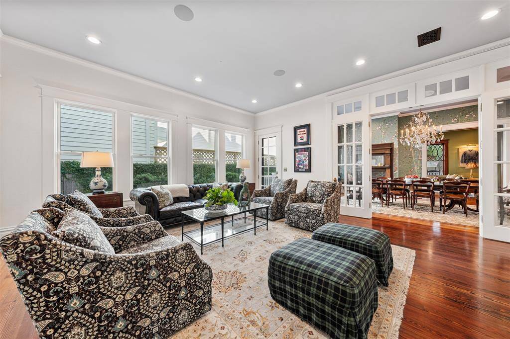 Walls of windows flood the room with natural light, giving it a solarium-like quality. Though open to the dining room, French doors allow it to be closed off for privacy or quiet moments.