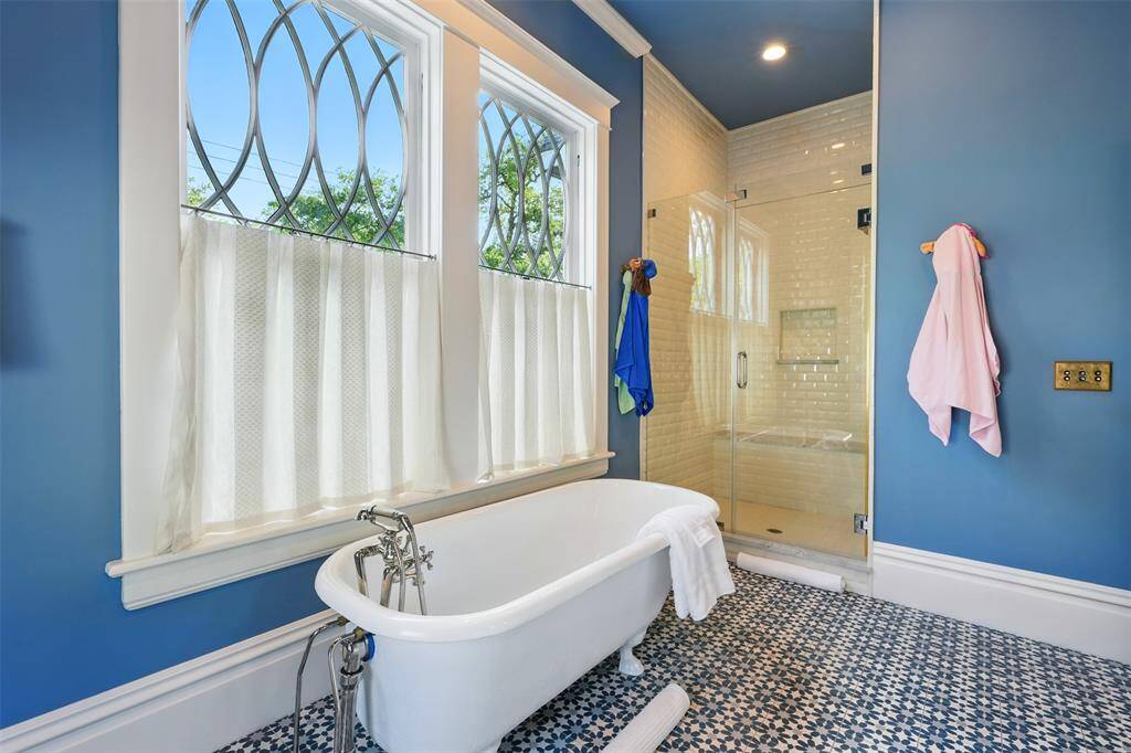 A spa-like space with vintage flair. A freestanding clawfoot tub sits beneath leaded-glass windows, while the adjacent walk-in shower with classic subway tile adds a crisp, modern touch to this charming retreat.