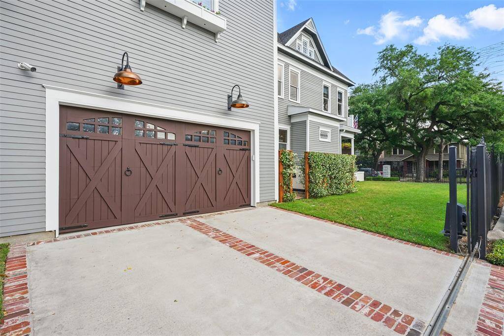 Secure, stylish, and seamlessly integrated. A gated driveway leads to a three-car garage with carriage-style doors and copper gooseneck lighting, blending form and function with historic curb appeal.