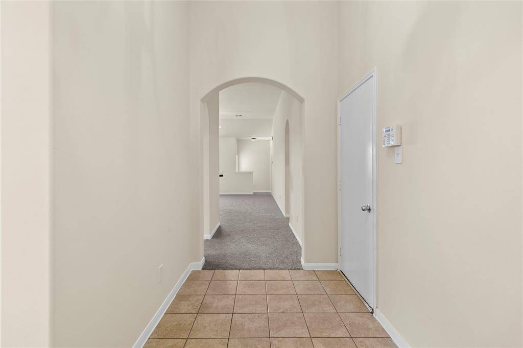 The entryway makes a clean, simple first impression with its neutral palette, tile flooring, and soft arch detail that draws your eye further into your main living area.
