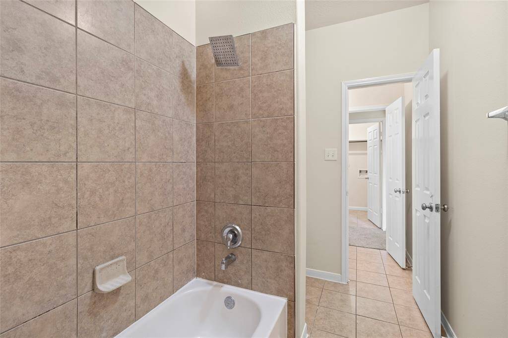 This secondary bath offers both a tiled shower and a soaking tub, with a thoughtful two-door layout that connects both sides of your home—perfect for added convenience and easy access for family or guests.