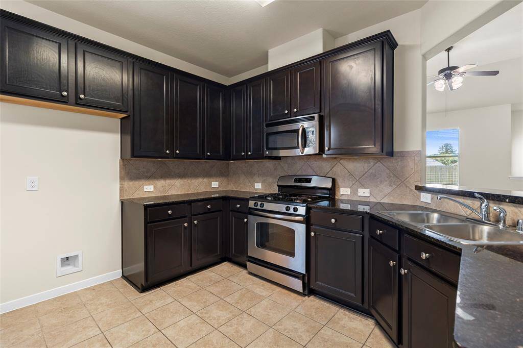 This kitchen offers a great blend of function and style with rich cabinetry, granite countertops, and stainless steel appliances—including a gas range and built-in microwave. The wraparound layout provides plenty of prep space, while the pass-through window keeps you connected to the living area.