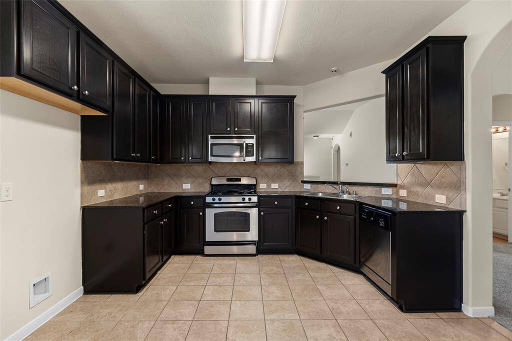 Sleek and functional, the kitchen is designed to handle everything from daily meals to weekend entertaining with ease. Outfitted with dark cabinetry, granite countertops, and a full suite of stainless steel appliances—including a gas range and built-in microwave—it balances style and practicality. The wraparound layout offers plenty of counter space and storage, while the open design keeps you connected to the main living area.