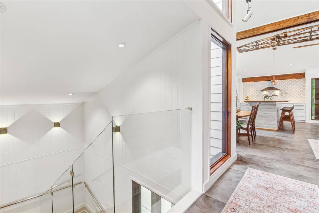 Modern staircase with English oak treads, leading to main living space with vaulted ceiling.