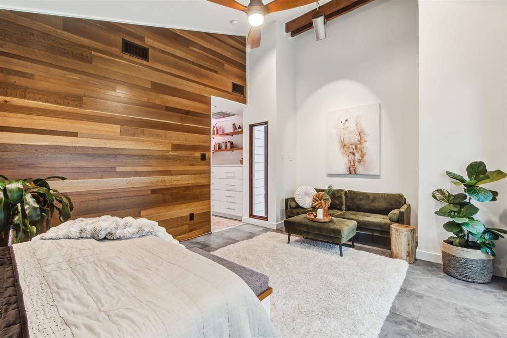 Primary bedroom is stunning with English oak feature wall reclaimed from Houston Chronicle building. Vaulted ceiling, tile floor, beams and ceiling fan.
