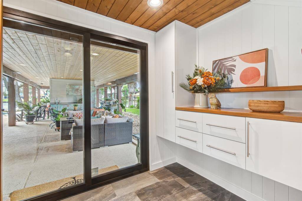 Entryway area showing hurricane patio doors to outside space. Raised custom cabinetry with soft close and teak counter and shelf.