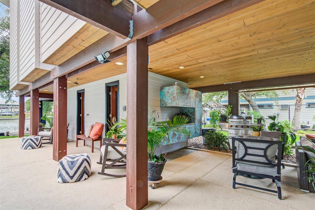 Outdoor kitchen area with lots of covered patio space, tongue and groove ceiling with recessed LED lighting. Doors to full bathroom and storage room.