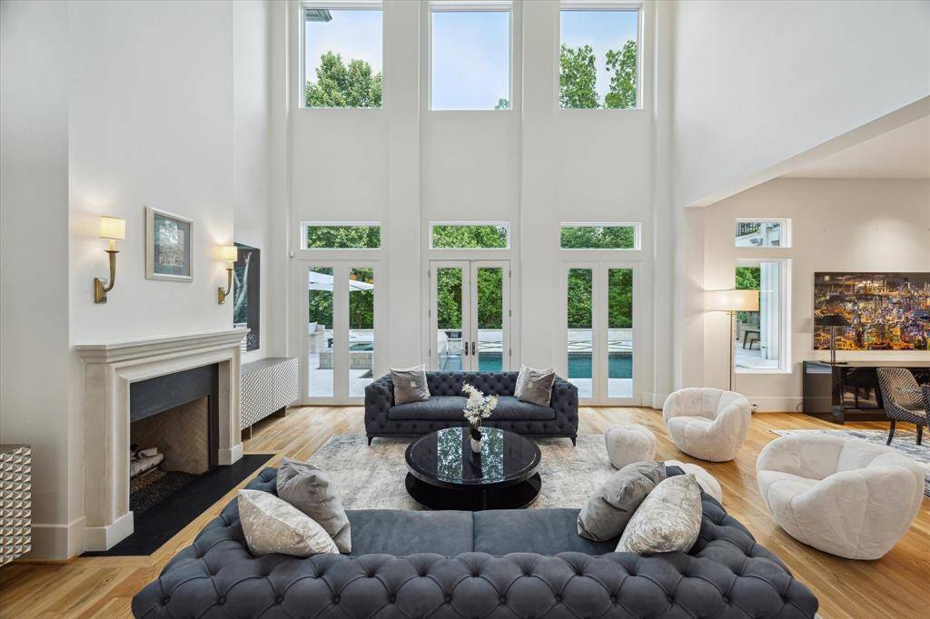 The living room with  soaring high ceilings and large windows flood the space with natural light, highlighting the elegant design.