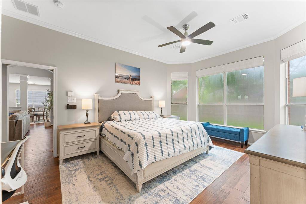 Spacious and bright bedroom featuring large windows, hardwood floors, and a ceiling fan, offering a serene and inviting atmosphere.