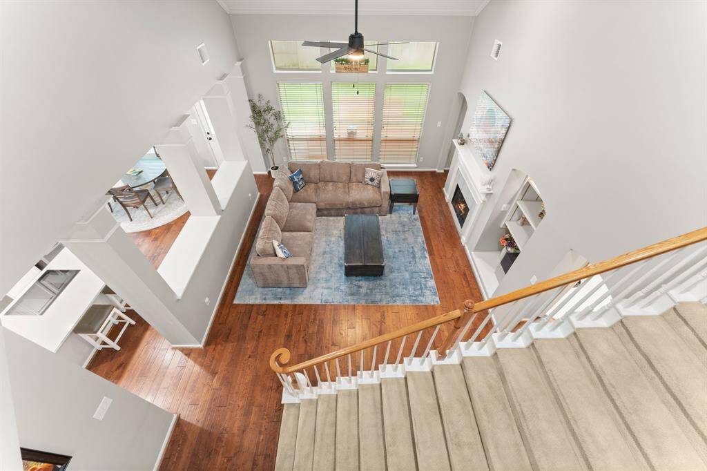 This spacious living area features high ceilings, a cozy carpeted staircase, and elegant hardwood floors. The room is brightened by ample natural light from tall windows, and there's a view into the adjacent dining area.