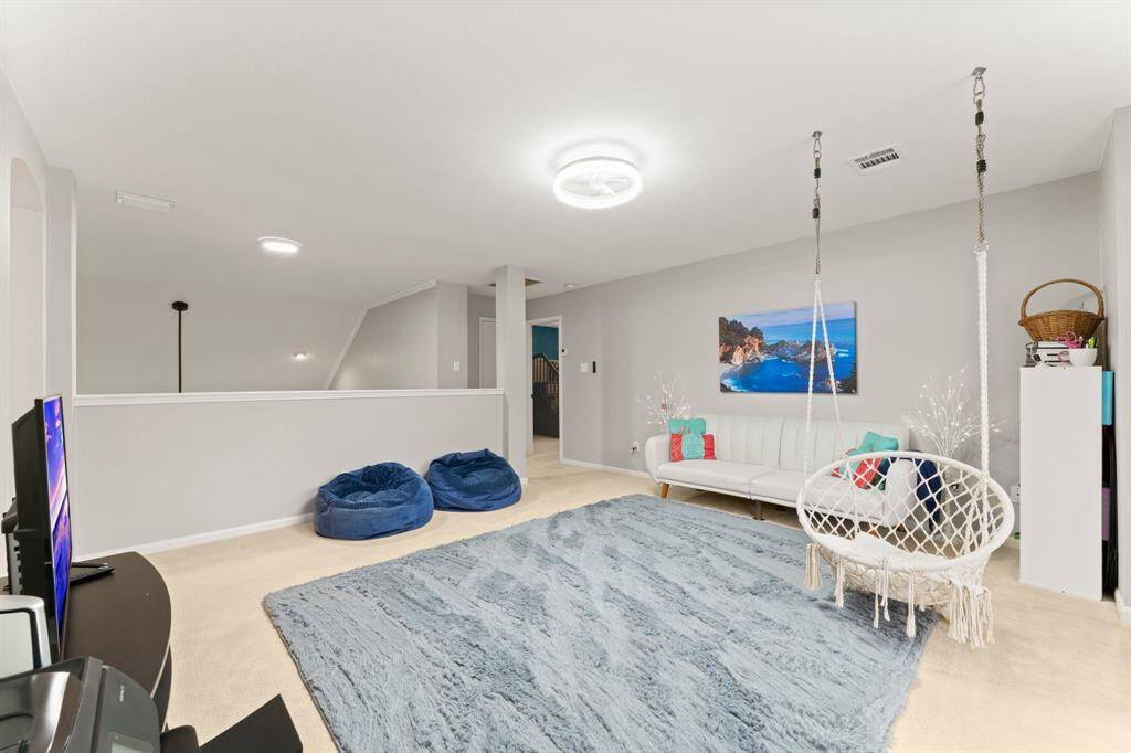 This spacious, light-filled room features neutral walls, a plush carpet, and ample natural light. Perfect for relaxation or entertainment, it has modern lighting and a stylish coastal wall art piece.