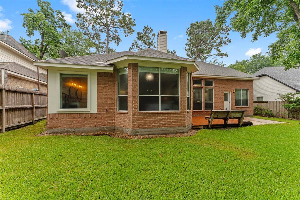 This charming brick home features a well-maintained backyard with lush grass, a wooden deck, and ample windows for natural light. Perfect for outdoor relaxation and entertaining.