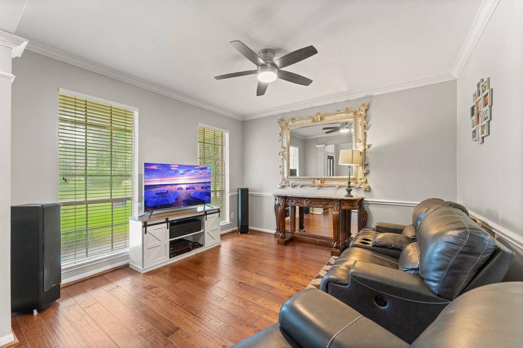 This cozy dining room features elegant hardwood floors ,natural light pours in through two tall windows, complemented by a modern ceiling fan.