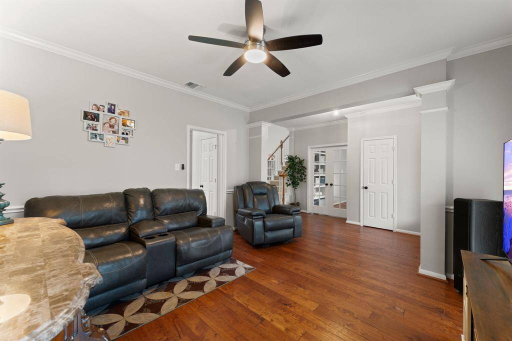 This inviting dining room features hardwood floors, a ceiling fan, The space is open and bright, with neutral walls and a view into a hallway with access to other rooms and a staircase.