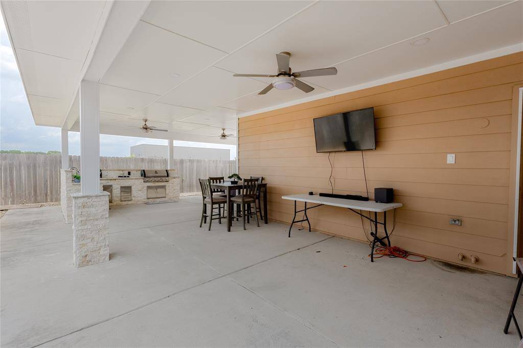 Spacious outdoor entertainment area with covered seating, ceiling fans, and a built-in grill, perfect for gatherings.
