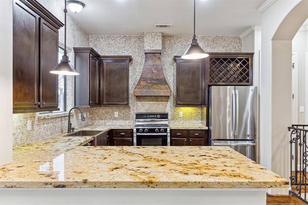 Spacious breakfast island with ample seating, featuring extensive custom mosaic tile work, pendant lighting, a copper sink, and under-cabinet lighting — blending style and functionality for the perfect gathering space.