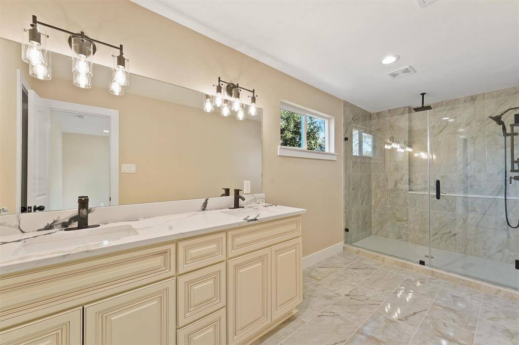 The Primary bathroom features a luxurious walk-in shower with sleek glass doors, creating a spacious and modern retreat for relaxation.