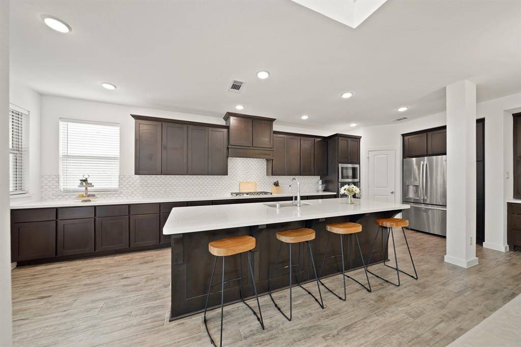 A 10' quartz surfaced island offers additional "prep" space along with breakfast bar seating and includes a stainless steel single basin under-mount sink overlooking the dining & living rooms.