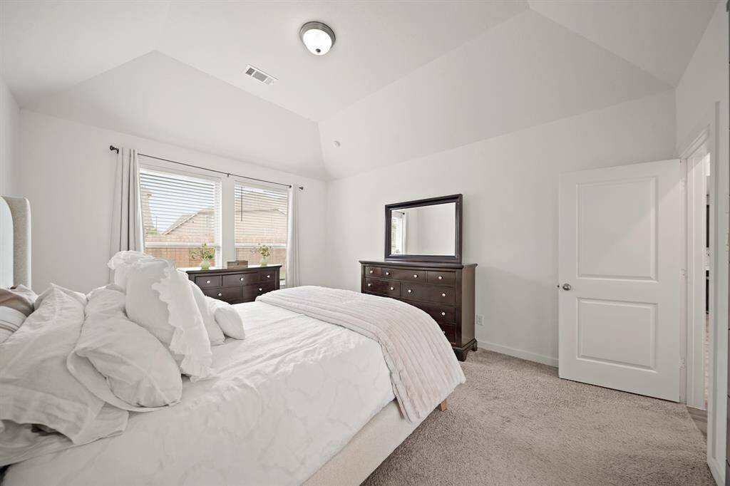 Features include a high ceiling with ceiling mounted lighting, windows with blinds overlooking the backyard & carpet.