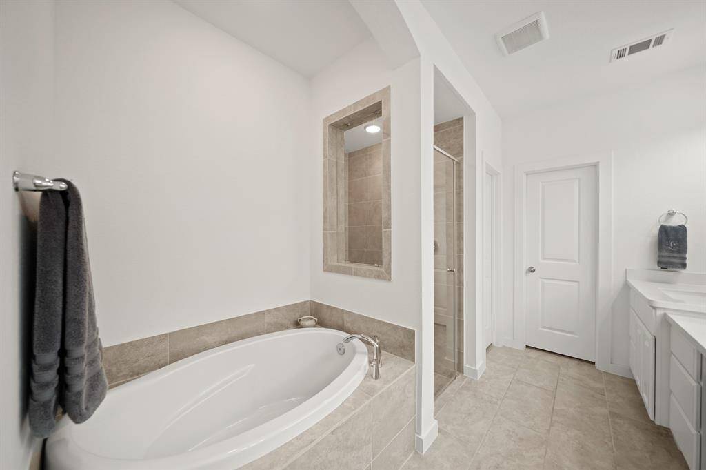 Relax & unwind in the tile surrounded soaking tub and nearby floor-to-ceiling tile surrounded & glass enclosed shower.