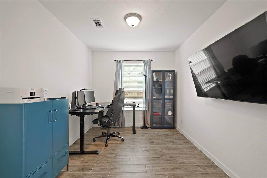 Accessible from the foyer, the private study has ceiling mounted lighting, pre-wiring for a wall mounted flat screen TV, a window with blinds overlooking the side yard and hardwood tile flooring.