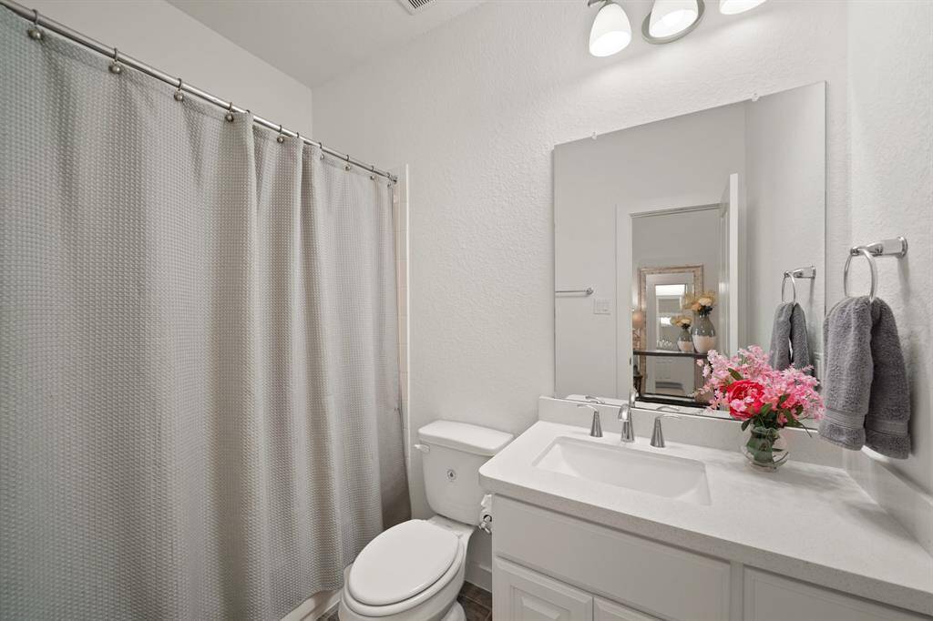 Convenient for guests, this second full bath located on the first floor of the home includes a painted cabinet supporting a quartz counter top with an under-mount sink & integrated back splash accompanied by wall mounted mirror & lighting, a ceramic tile surrounded combination tub/shower & tile flooring.