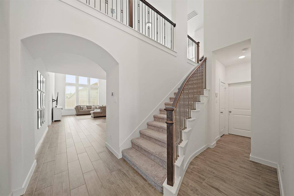 A view of the wrought iron staircase leading to the second level of the home. Access to the utility room and the home's two-car attached garage is shown in the background on the right.