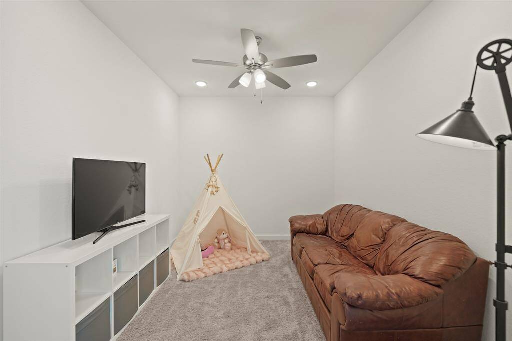 Flowing seamlessly from the game room is a media room with recessed lighting, ceiling fan with lighting & carpet.