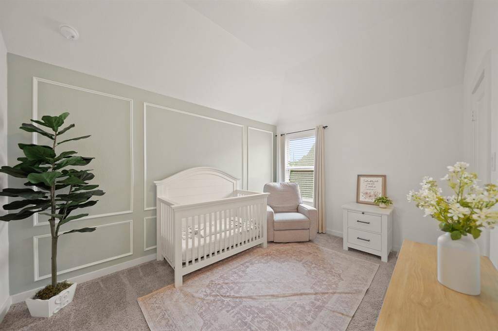 The third bedroom includes a high ceiling with ceiling mounted lighting, window with blinds overlooking the side yard, a painted accent wall with picture frame moulding & carpet.