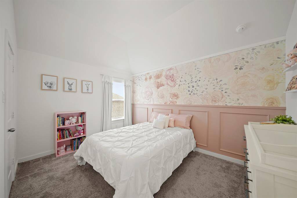 The fourth bedroom has a high ceiling with ceiling mounted lighting, window with blinds overlooking the side yard, a wallpapered and accent painted wall with crown & picture frame moulding & carpet.