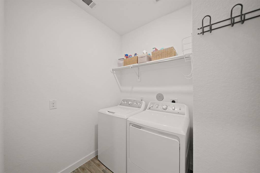 The first floor utility room with ceiling mounted lighting includes upper shelf & hanging wardrobe storage along with hardwood tile flooring.