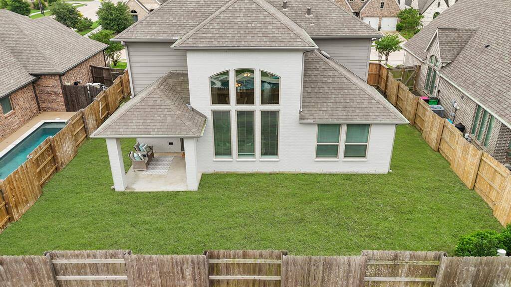 An aerial view of the home illustrating the roof lines, fenced backyard and covered patio.