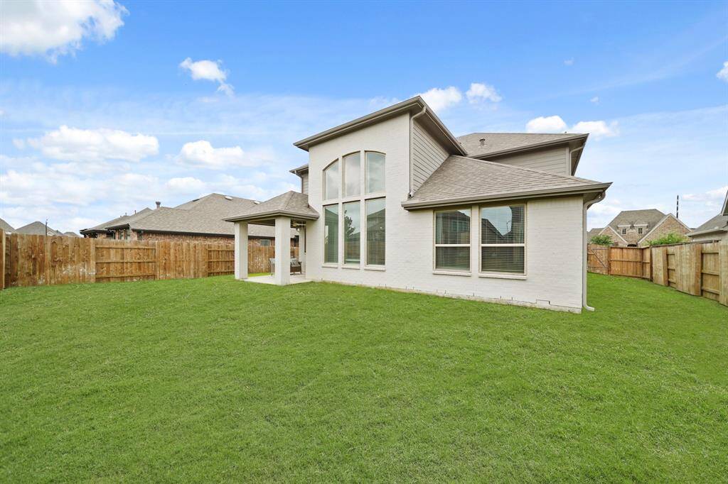 A view of the back of the home, spacious side yards & fully fenced backyard.