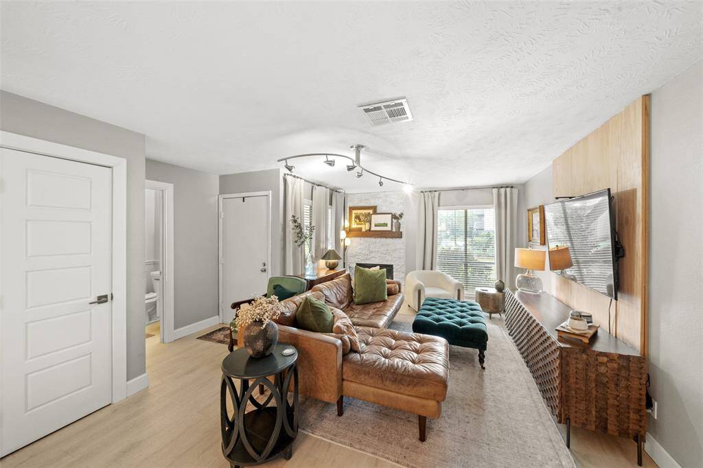 This living room features a cozy and inviting design with a large,  fireplace, and ample natural light from the windows. The room is accented with stylish lighting.