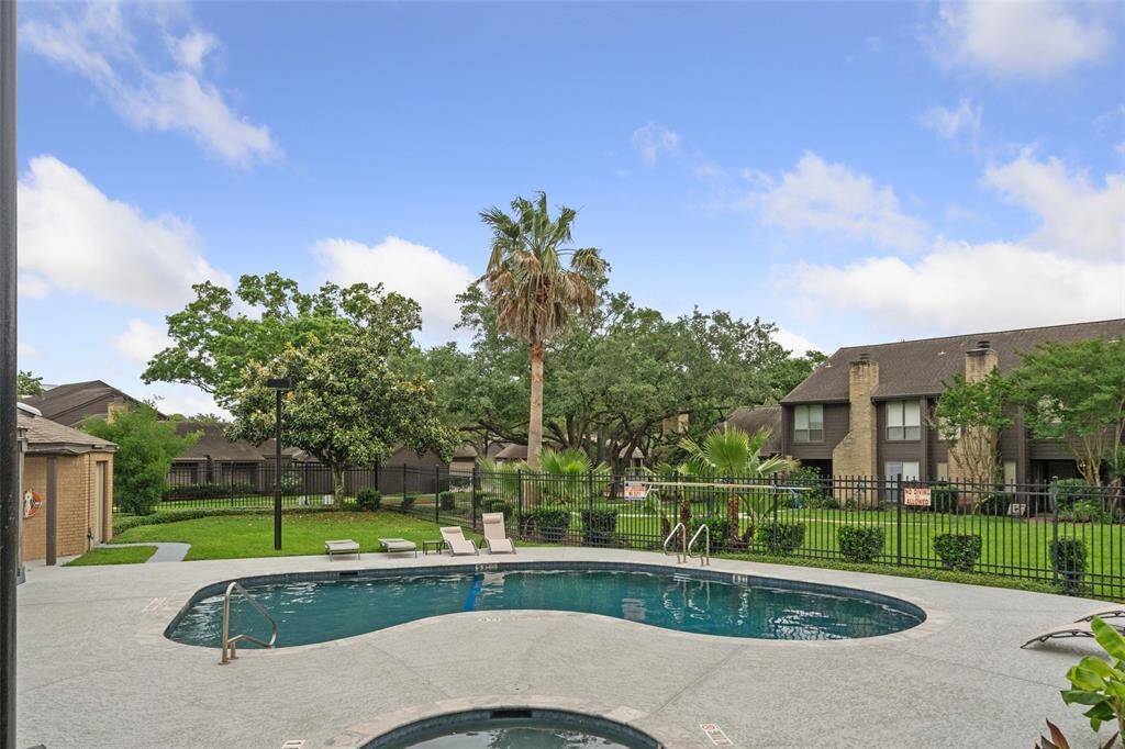 This photo showcases a community pool area , surrounded by well-maintained greenery and residential buildings. It's a serene setting perfect for relaxation and leisure.