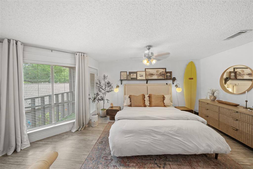 This bedroom is bright and inviting, featuring a large window. A ceiling fan adds comfort offering both functionality and charm.