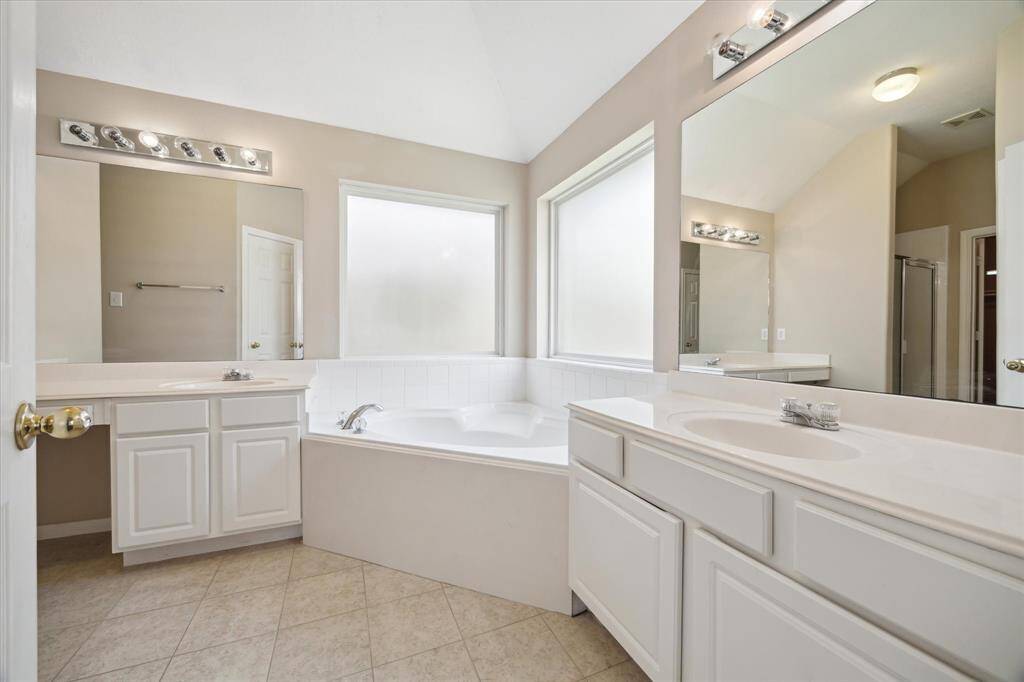 The luxurious primary bathroom features a spacious vanity, oversized tub, and separate shower.