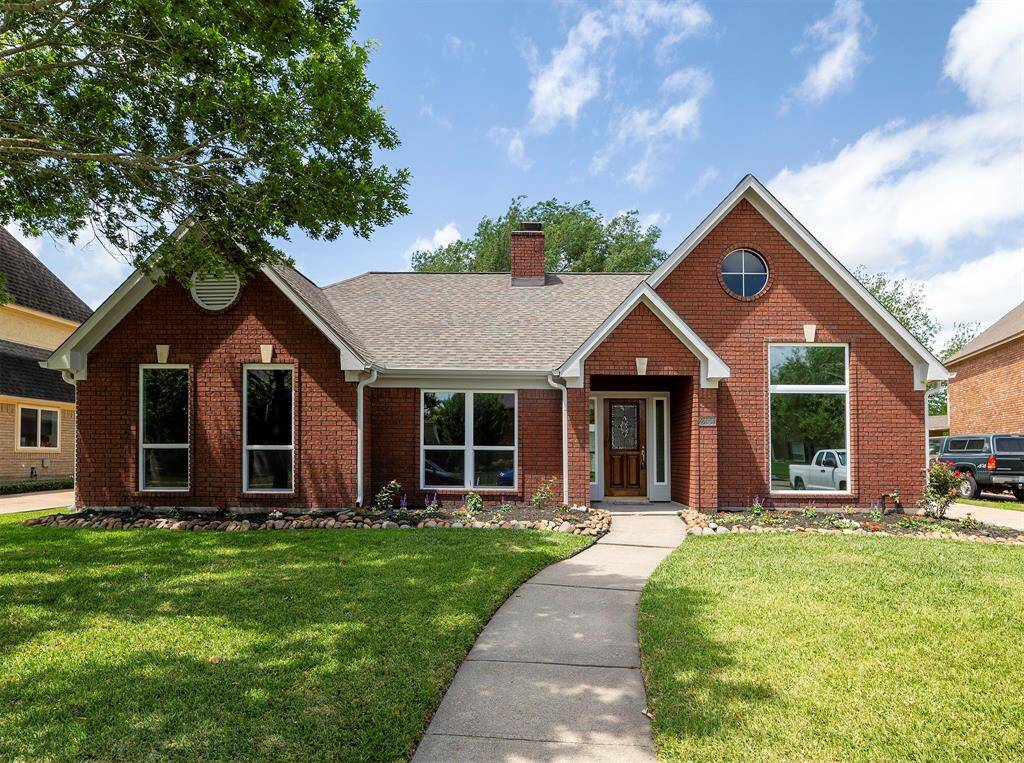 This charming brick home features a well-maintained front yard with a curved walkway leading to an inviting entrance. Large windows provide ample natural light, and the gabled roof adds to its classic appeal. Perfect for those seeking a welcoming and attractive exterior.